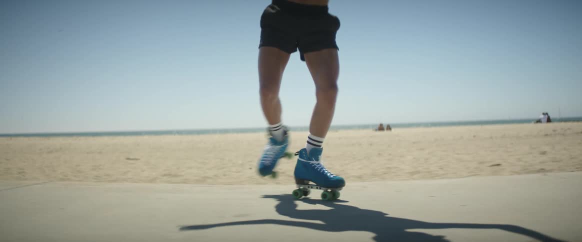 Person on skating shoe walking on a path near the beach on a sunny day