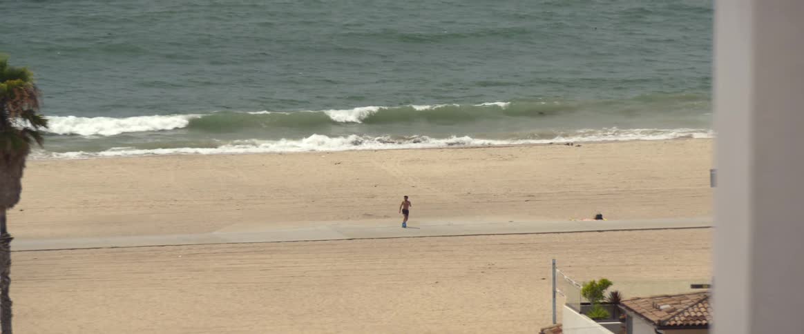 A man using roller skates and dancing on the beachside sidewalk