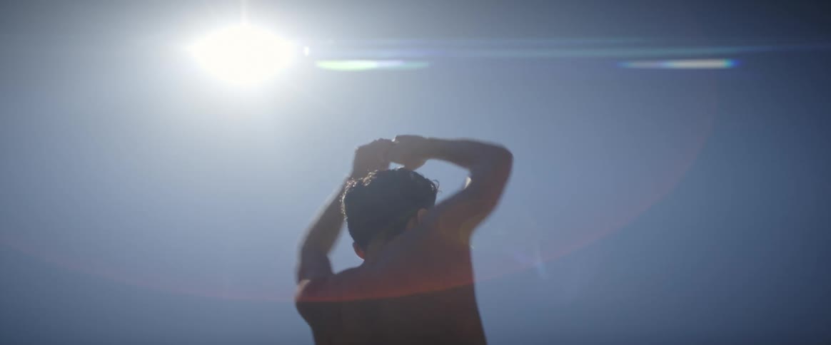 Portrait of a shirtless man spinning with his hands above his head