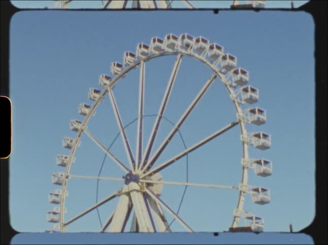 A view of a massive ferris wheel in motion on a clear sky day