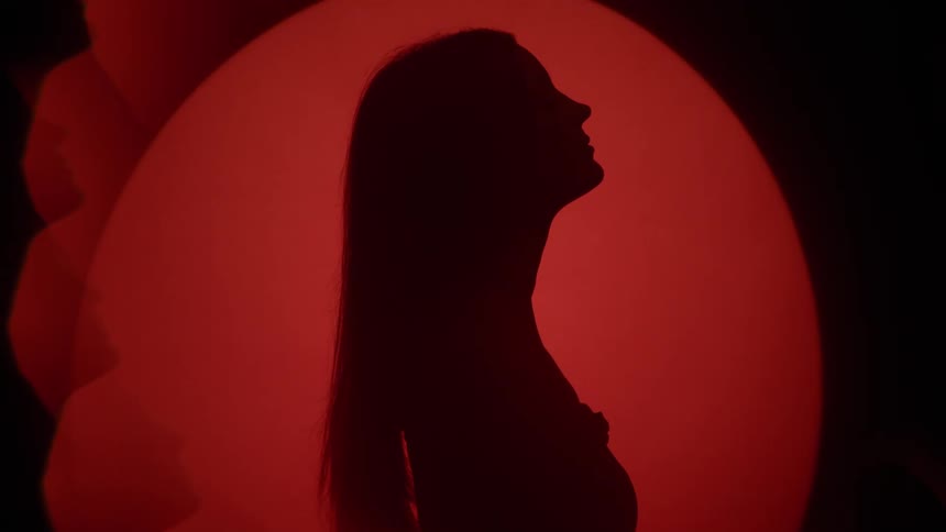 The silhouette of a woman in profile against a black and red background