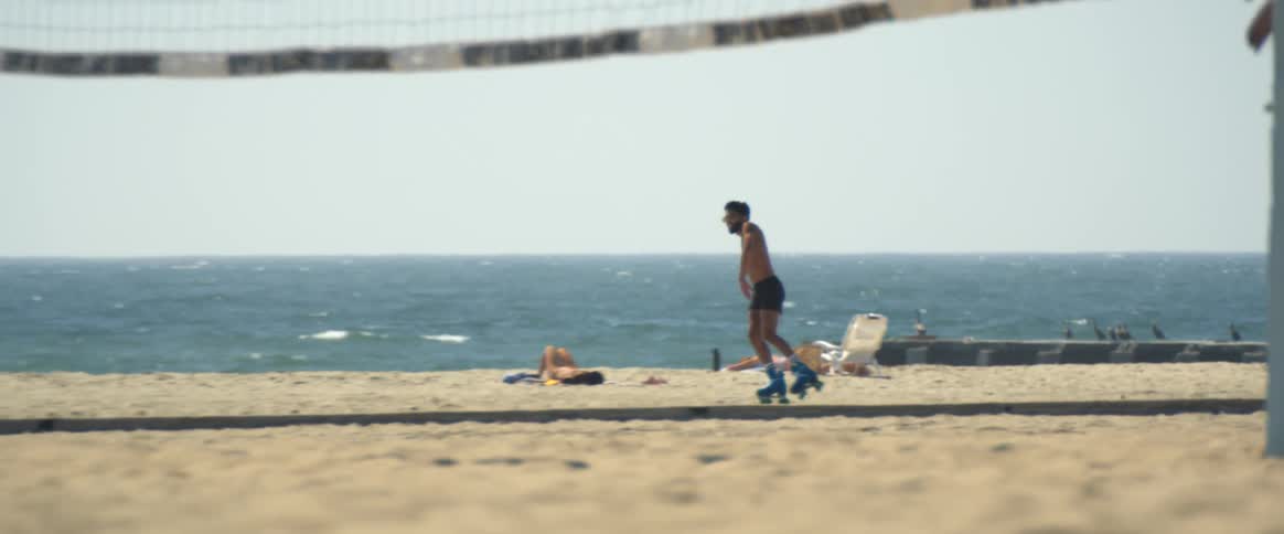 A man dancing with his roller skates on the beach during the summer