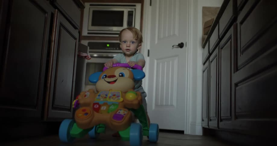 A toddler playing and walking with a toy car