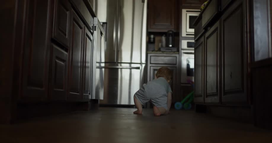 Baby crawling on the kitchen floor at midday