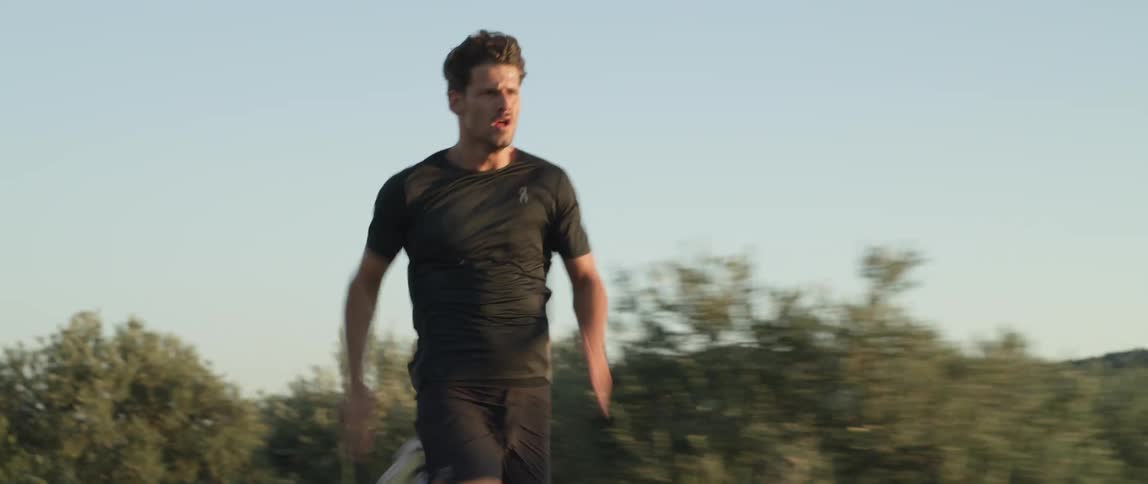 A man runs incredibly fast along a paved road on a sunny day