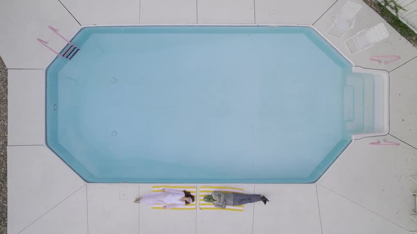 A woman and an alien lying on the edge of the pool
