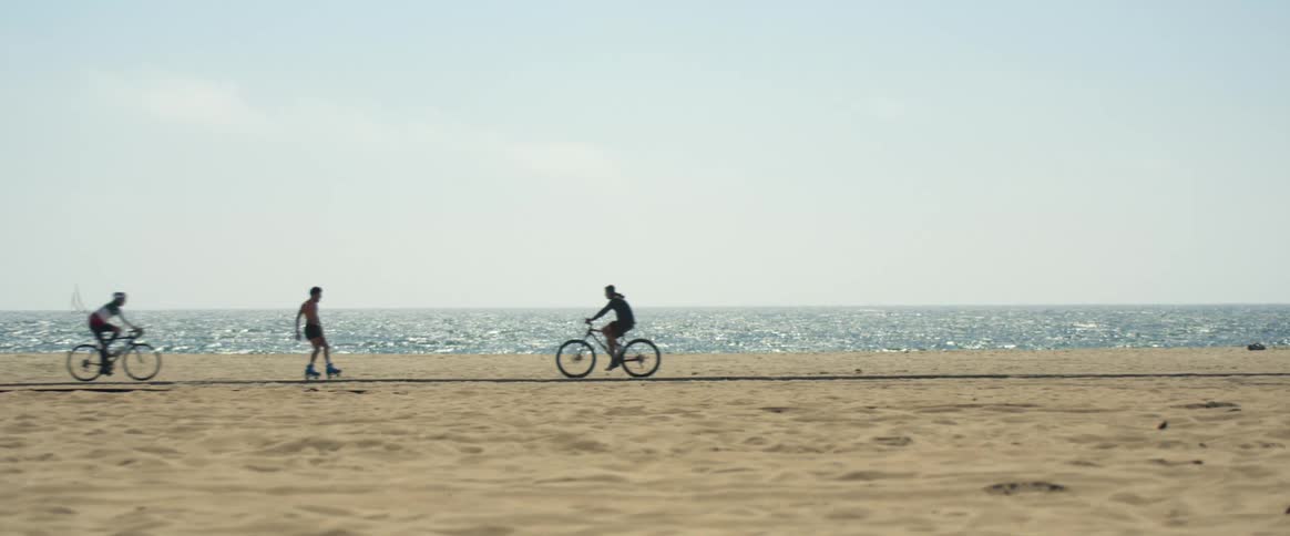 People riding bicycles and rollerblading on the bike path at the beach