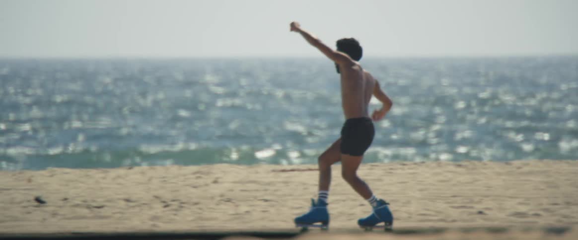 A man roller skating on the beach and dancing