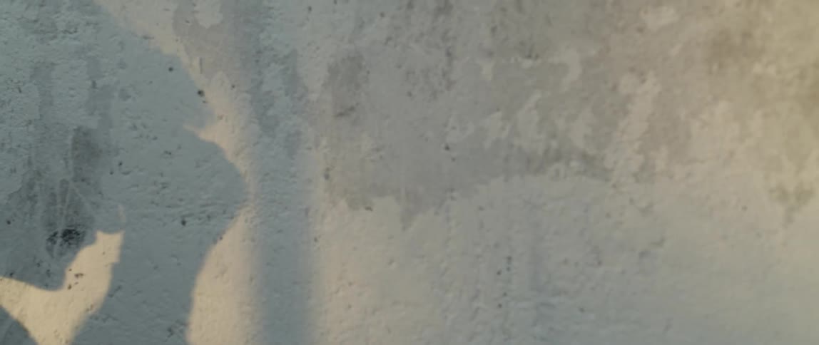 A young man is shadow boxing next to a concrete wall