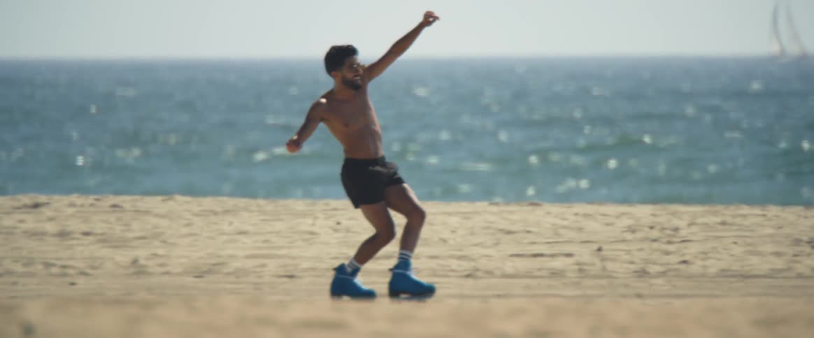 A man walking on blue roller skates on the beach
