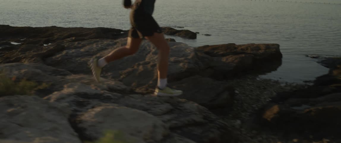 A man running on the rocks by the seaside at dawn