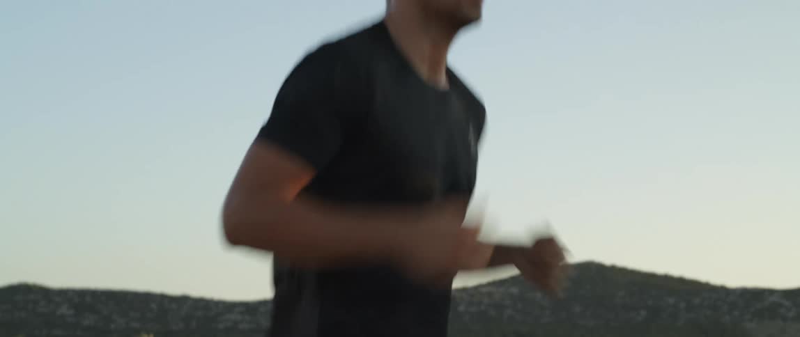 Man runs along road through countryside passing fields and hills