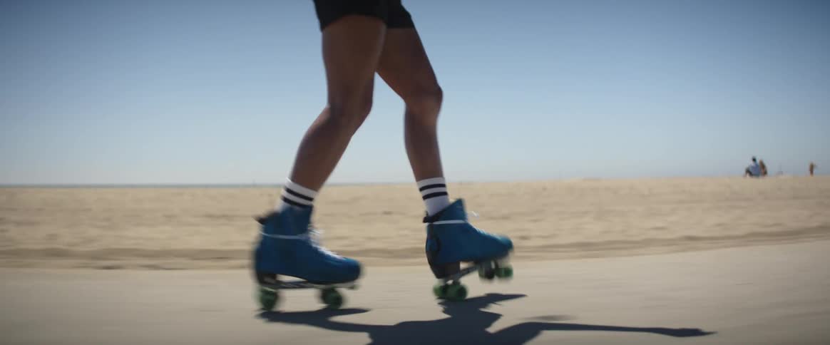 A closeup of a persons legs roller skating on the beach
