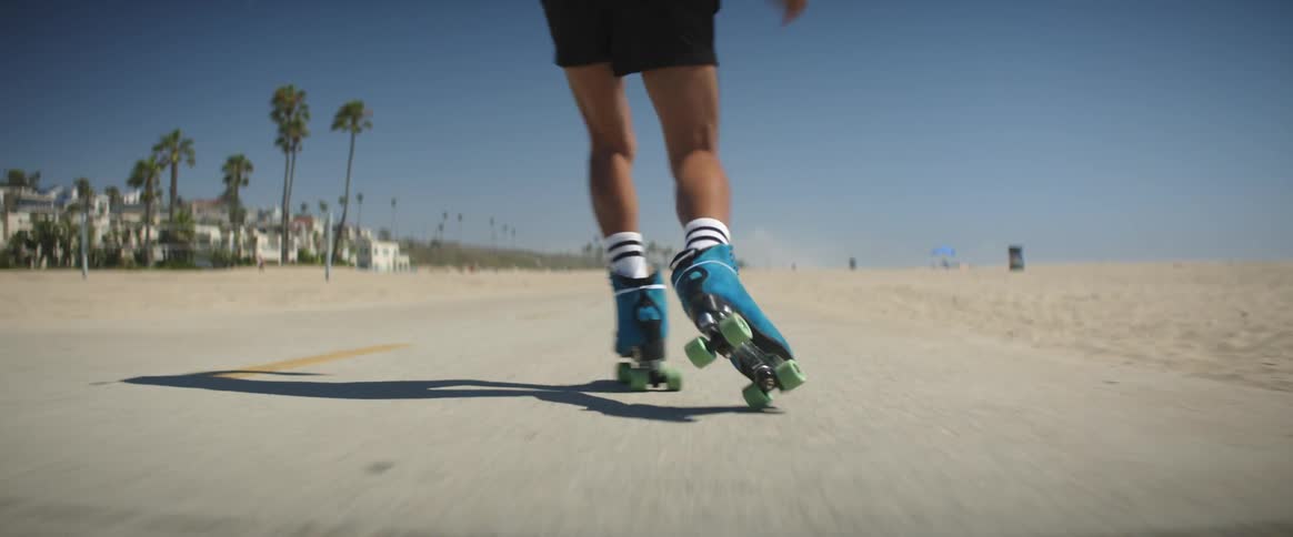 Male skater performs rollerskating moves on beach road