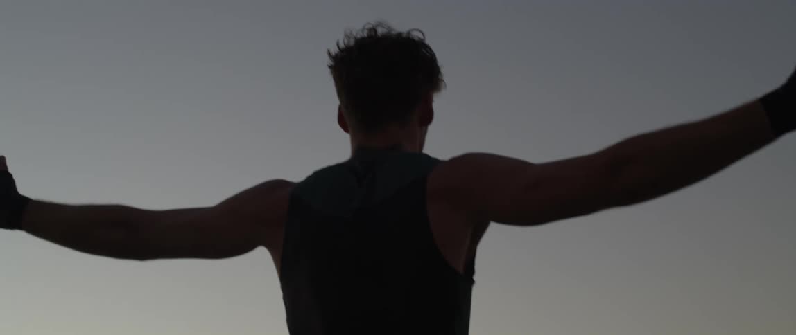 A man stretches his arms out on the shore
