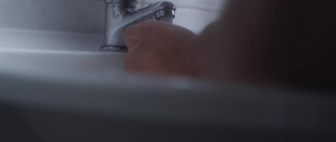 Man washes his hands on the bathroom sink