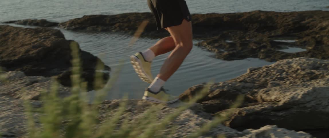 Legs of a man running on the rocks by the seaside at dawn