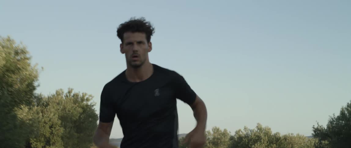 A man running on a road in a lush green environment