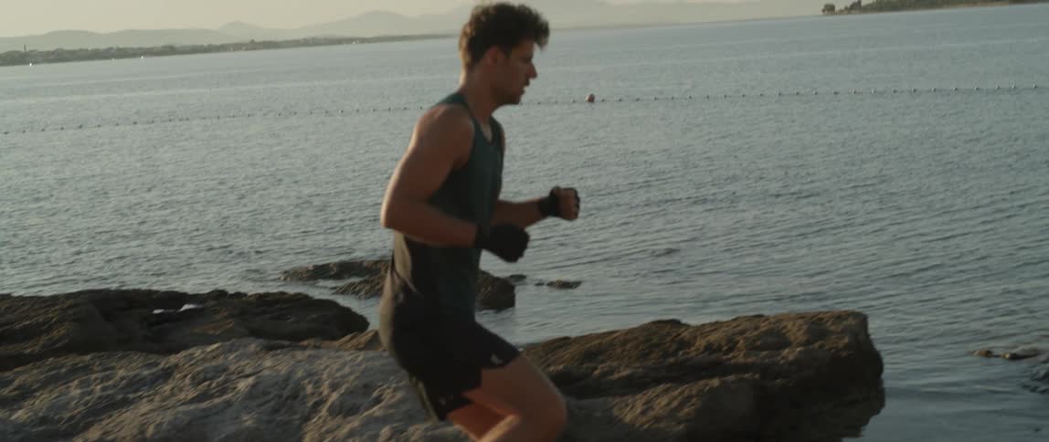 A man running on top of rocks by the seaside