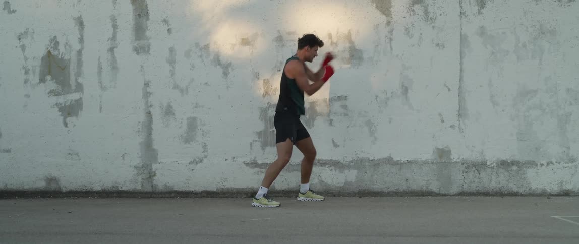 Man practices punches while standing next to wall with peeling paint