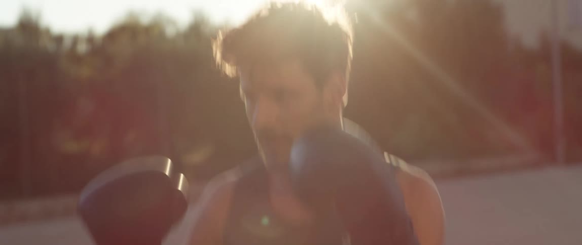 A man training with a partner on boxing punches in an outdoor setting
