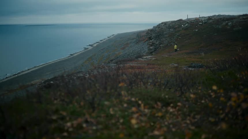 Man walks up hill away from beach on cloudy day