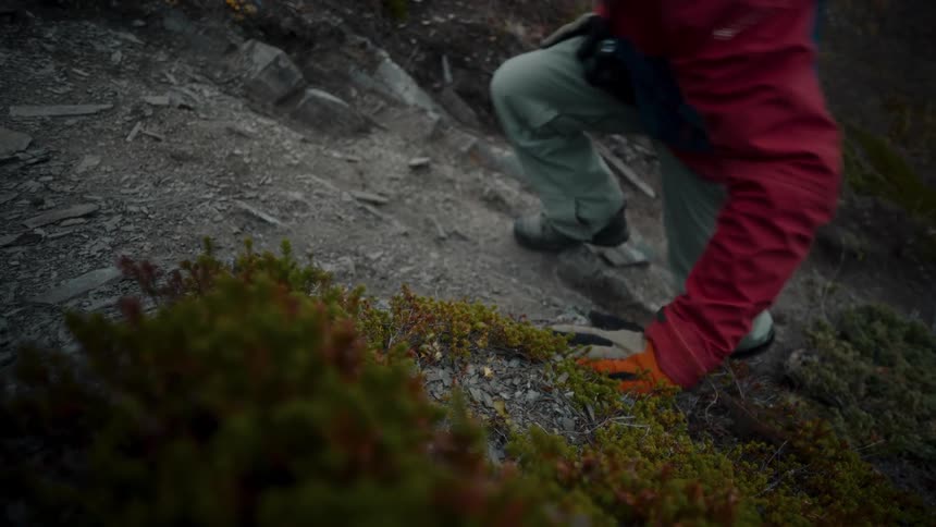A man with a camera around his neck climbs a ridge