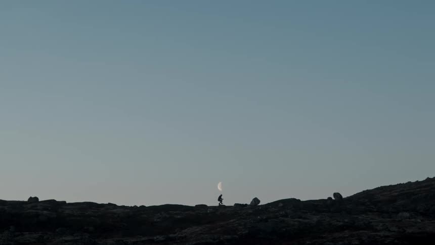 A person walking on a rocky mountain near dusk