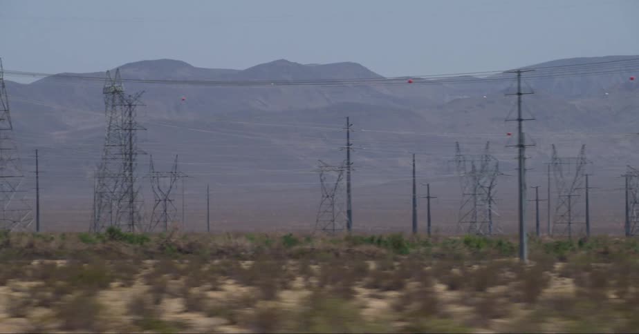 Transmission towers with cables on a big land at midday
