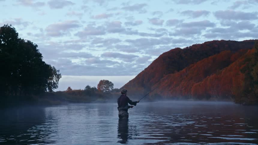 Man fishing on a calm lake in the mountains at morning