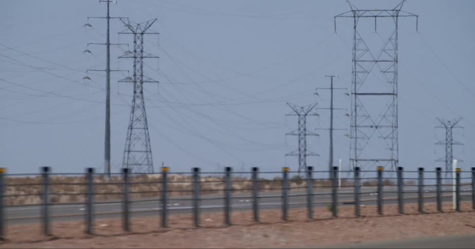 Transmission towers and moving vehicles at midday