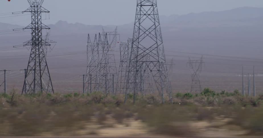Power lines and transmission towers in the desert seen from a moving vehicle