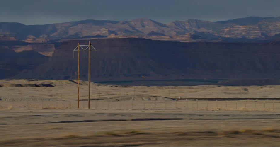 View of electrical towers in an outdoor environment with a mountain range nearby and a road alongside