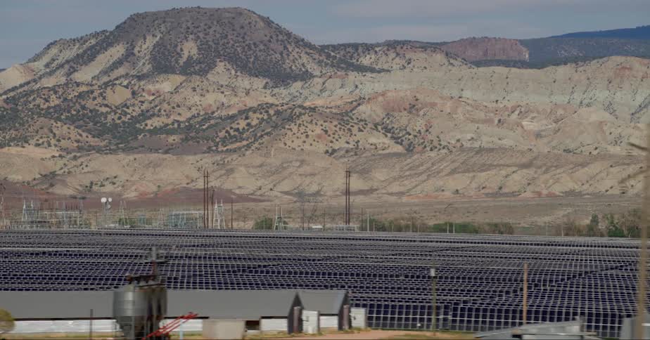 Several solar panels on the ground with a mountain range in the background