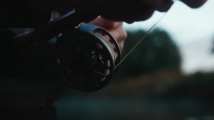 Hands of a person setting up a fishing reel with fishing line
