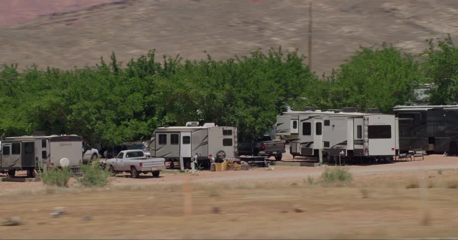 Recreational vehicle campers parked under trees near roadside
