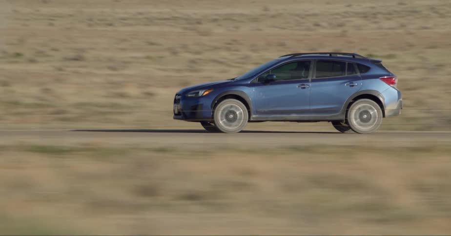 A sport utility vehicle drives at a high speed along a remote road