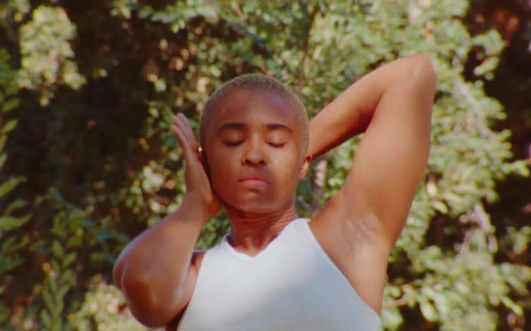 A woman dancing and gesturing her arms around her head