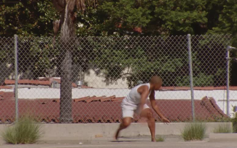A black man stretching his body on a playground on a sunny day