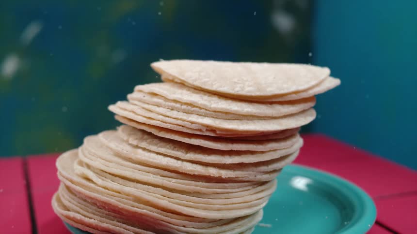 Stack of tortillas falls through air to land on plate