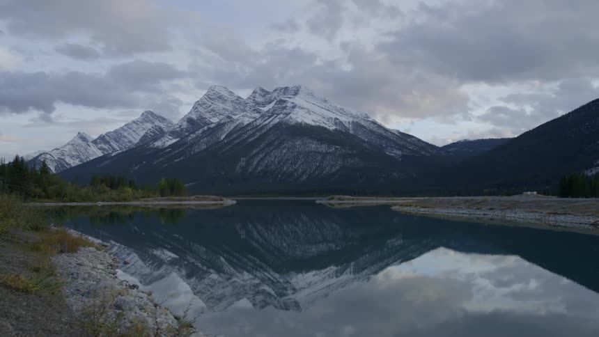 The water of a lake is reflecting a snow covered mountain