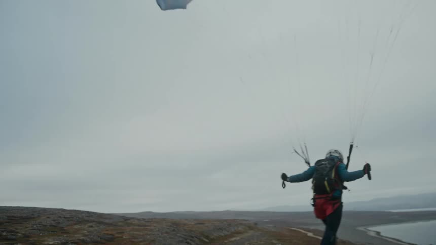 A man with a parachute running and jumping