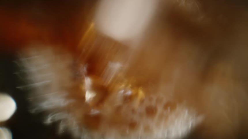Extreme closeup of a liquid drink being poured into a glass cup