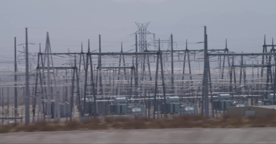 Power station and transmission towers in the desert near a freeway