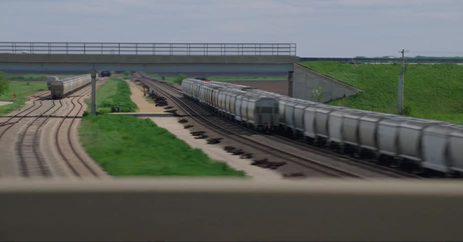 Trains park on train tracks near multiple bridge on cloudy day