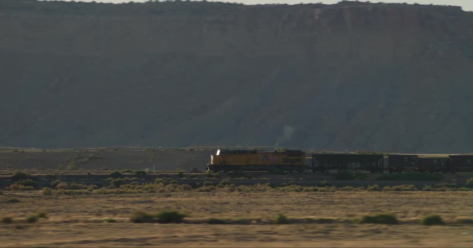 Freight train in the field with mountains in the background