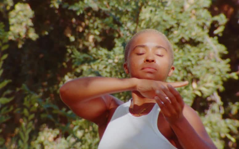 A dancer performs a series of motions using their arms hands and fingers sometimes looking at the camera other times looking up or down