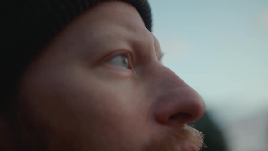A close up of a mans head intently watching something pass by him
