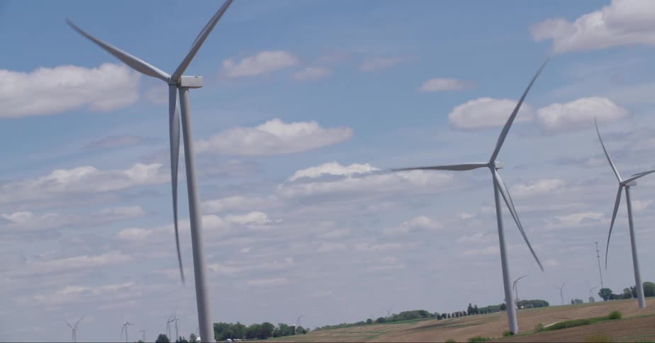 Wind turbines on a rural windfarm spin under a cloudy sky