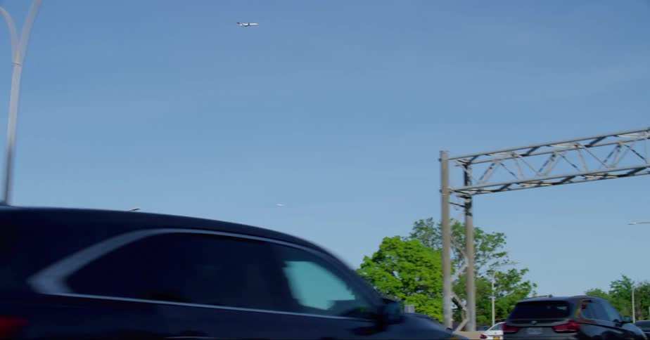 Passenger plane flying in the sky seen from vehicle driving on highway